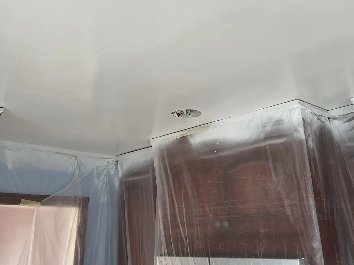 Kitchen cabinets masked in plastic before the ceiling is sprayed
